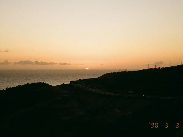 Un hermoso atardecer sobre el mar con montañas en primer plano.