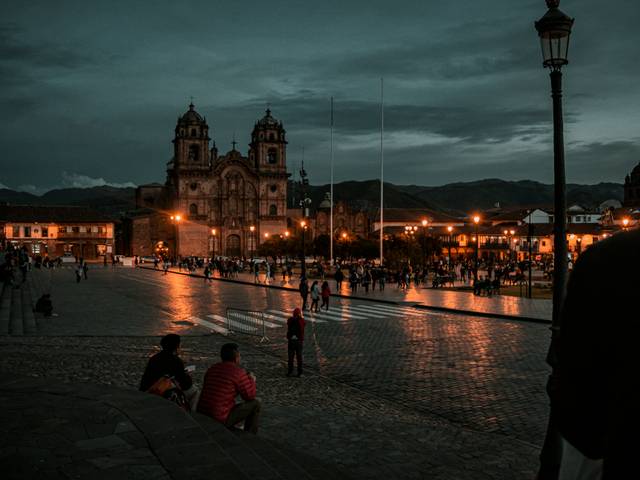 Una plaza iluminada al atardecer con una hermosa arquitectura de fondo en Cusco, Perú.