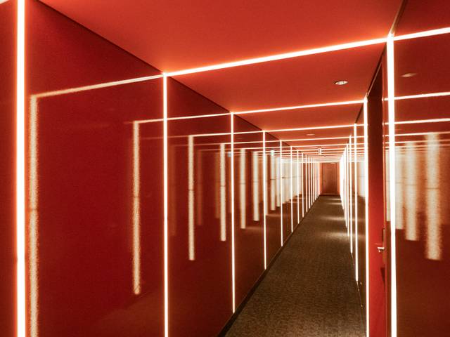 Un pasillo iluminado con luces brillantes sobre un fondo rojo.