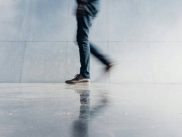 Una persona camina sobre una superficie reflectante en un entorno minimalista.