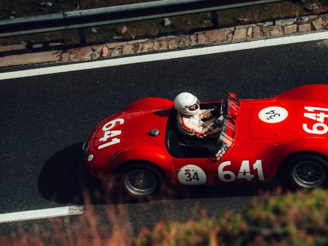 Un coche de carreras rojo circulando por una carretera montañosa.