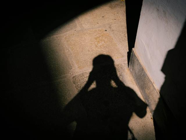 La imagen muestra la sombra de una persona proyectada sobre un suelo de piedra.