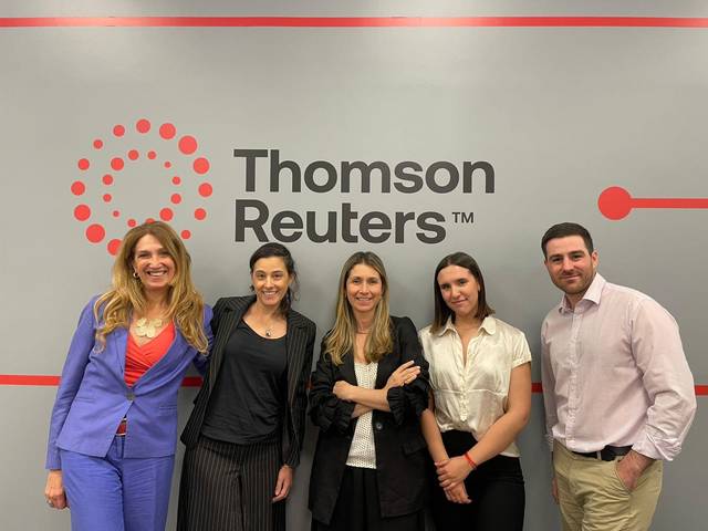 Un grupo de cinco personas posando frente a un logotipo de Thomson Reuters.