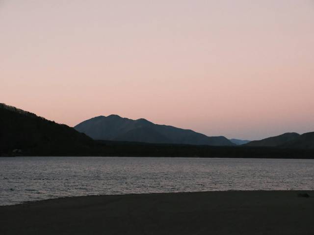 Un paisaje sereno al atardecer con montañas y un lago tranquilo.