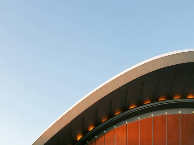 Una vista de un edificio moderno con un techo curvado destacado por luces integradas.