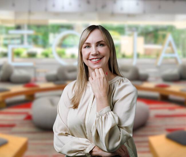 Una mujer sonriente se encuentra en un ambiente moderno y acogedor.