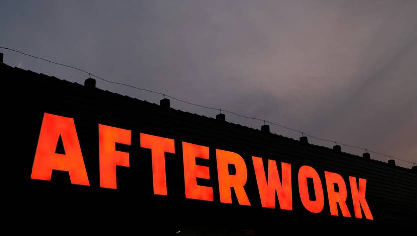 Un letrero luminoso que dice 'AFTERWORK' contra un fondo de atardecer.