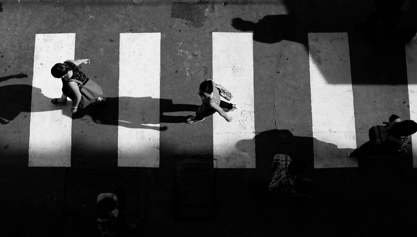 Una vista aérea de personas cruzando un paso de peatones con sombras marcadas.