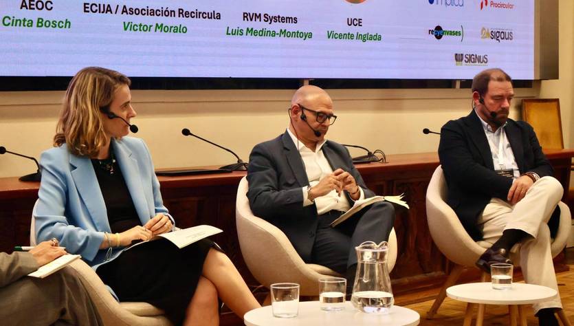 Un panel de tres ponentes discutiendo en un evento, con un fondo que muestra varios logos de empresas.