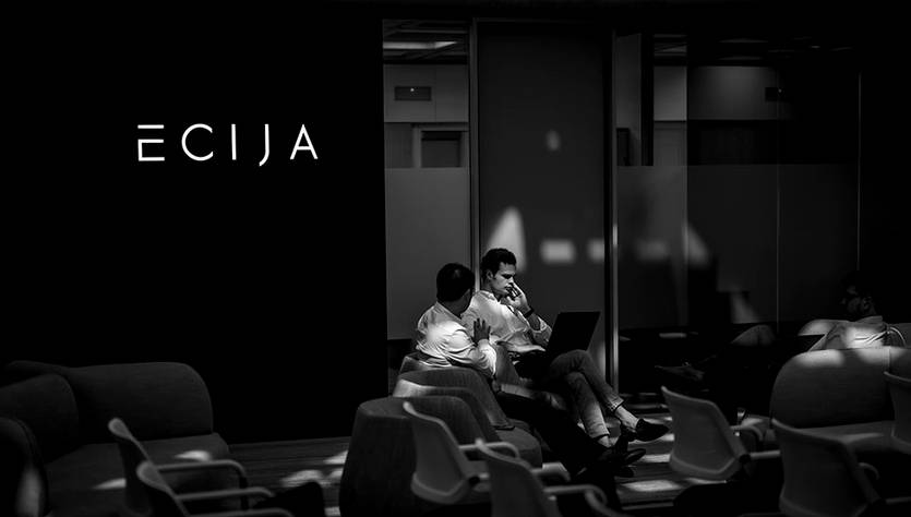 La imagen muestra un ambiente de oficina en blanco y negro con el logotipo de 'ECIJA' y dos personas sentadas en un sofá, conversando y trabajando en un portátil.