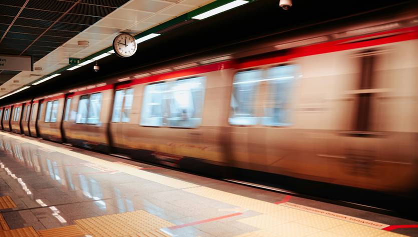 Un tren de metro se mueve rápidamente por una estación subterránea.