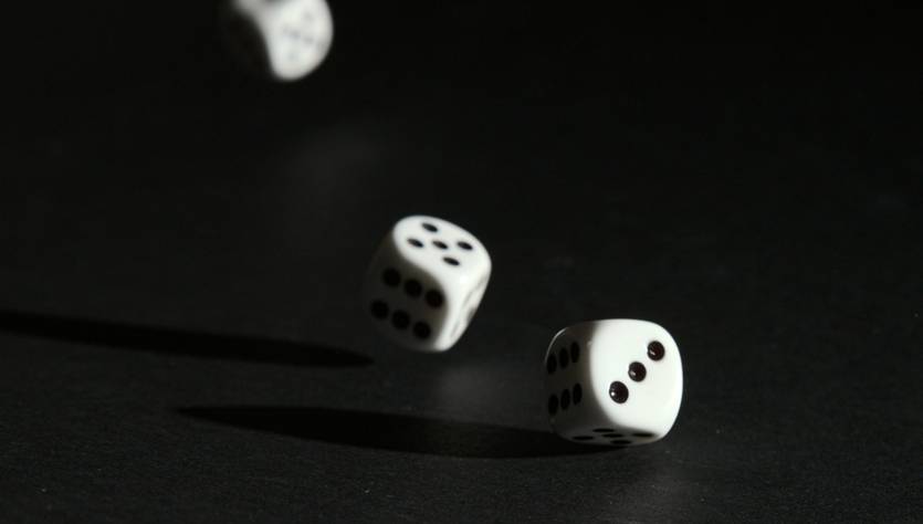 Tres dados blancos en movimiento sobre un fondo oscuro.