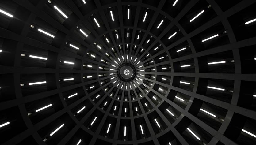 Una vista desde abajo de una estructura circular con luces que emanan de las paredes en un patrón radial.