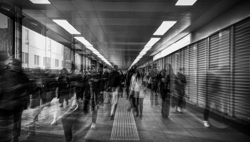 Una multitud de personas camina por un pasillo iluminado en un entorno urbano.