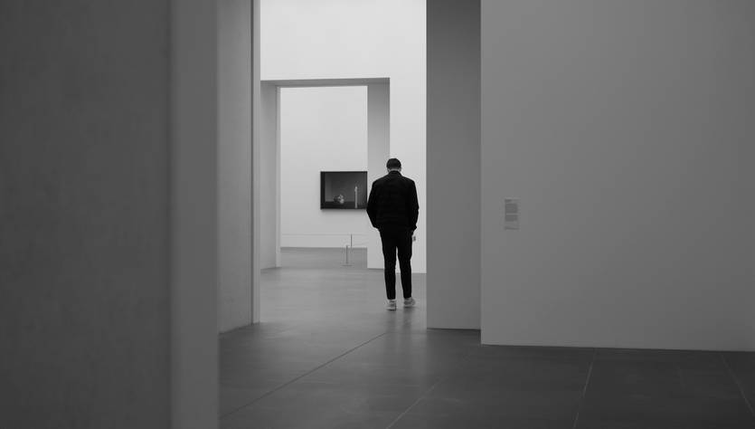 Una persona observa una obra de arte en una galería minimalista.