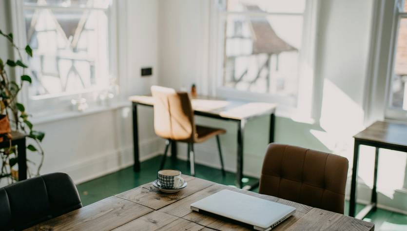Una habitación luminosa con una mesa de madera, una computadora portátil y sillas elegantes.