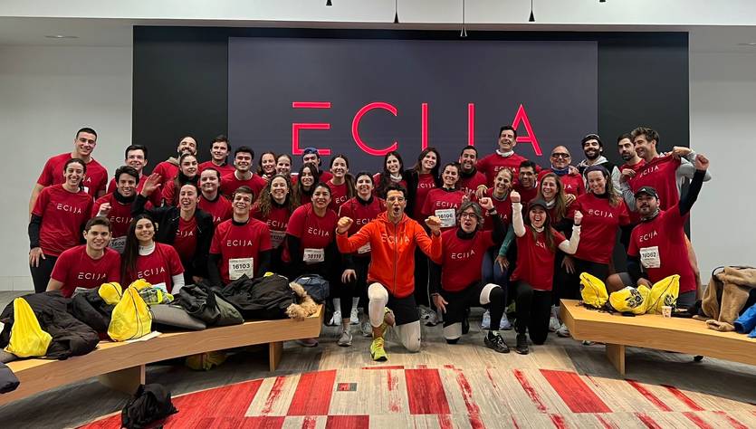 Un grupo grande de personas sonrientes posando en un ambiente interior con camisetas rojas.