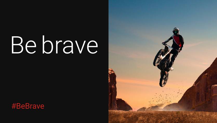Un motociclista realizando un salto en un paisaje desértico al atardecer.