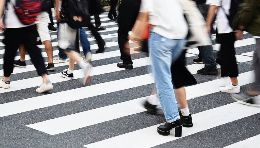Una multitud de personas cruza una calle en un paso peatonal.