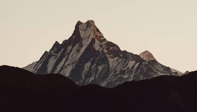 Una imponente montaña con picos nevados al atardecer.