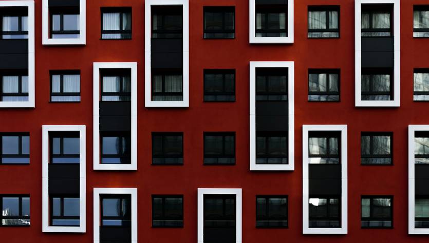 Una fachada de edificio con un diseño moderno en color rojo y ventanas de diversas formas.