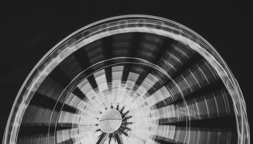 Una noria iluminada en movimiento, capturada en un estilo artístico en blanco y negro.