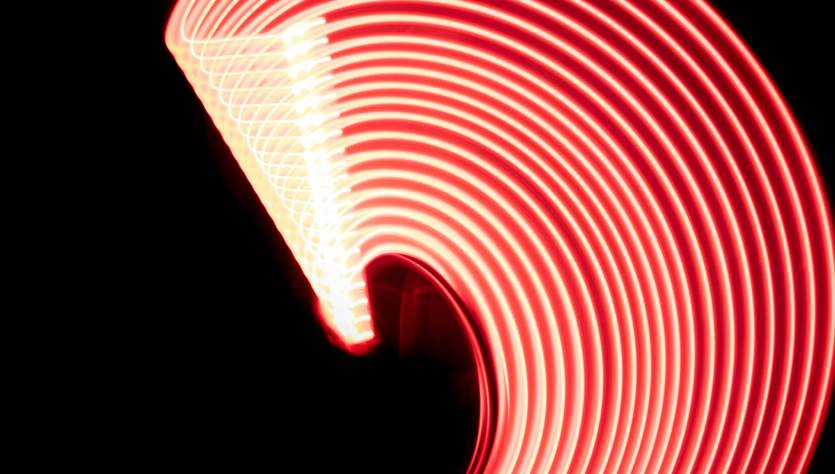 Una serie de luces rojas formando un arco luminoso sobre un fondo oscuro.
