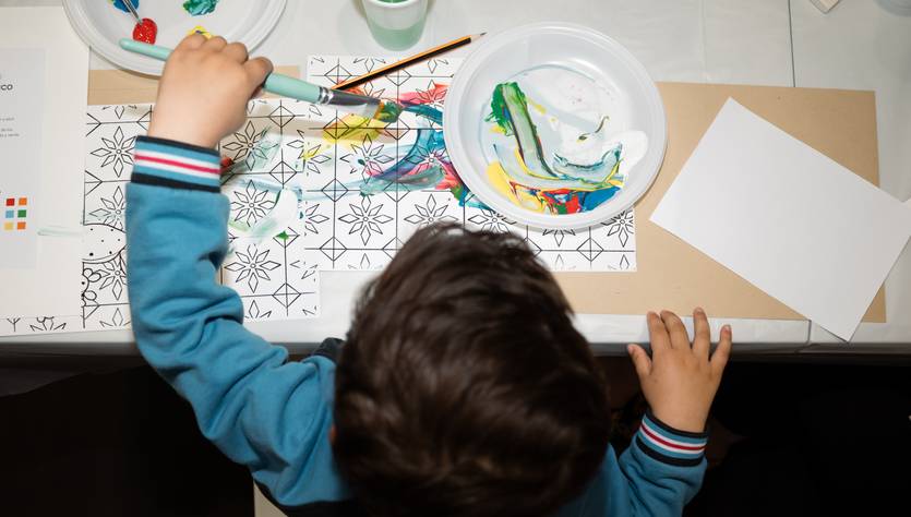 Un niño pintando sobre una hoja con colores en un ambiente creativo.