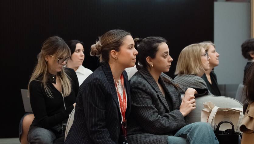 Un grupo de mujeres sentadas en un ambiente moderno, prestando atención en un evento.