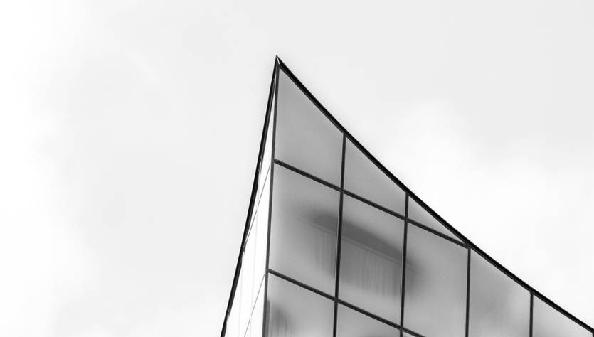 La imagen muestra la esquina superior de un edificio moderno con fachadas de vidrio.