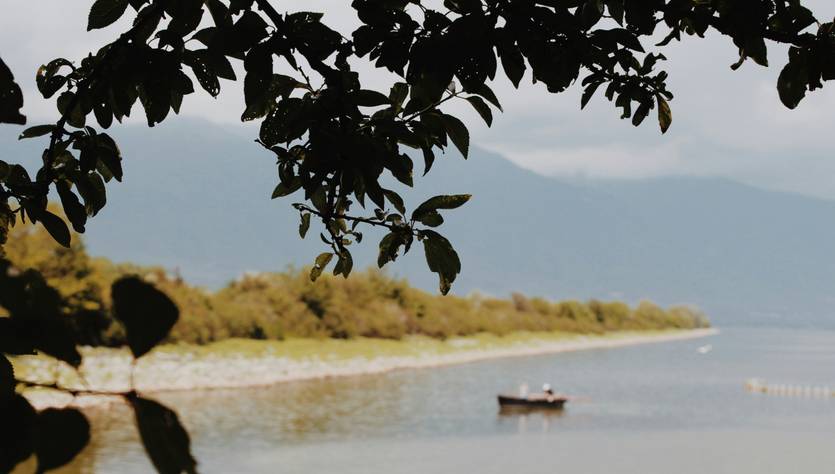 Una vista tranquila de un lago con un bote y montañas al fondo.