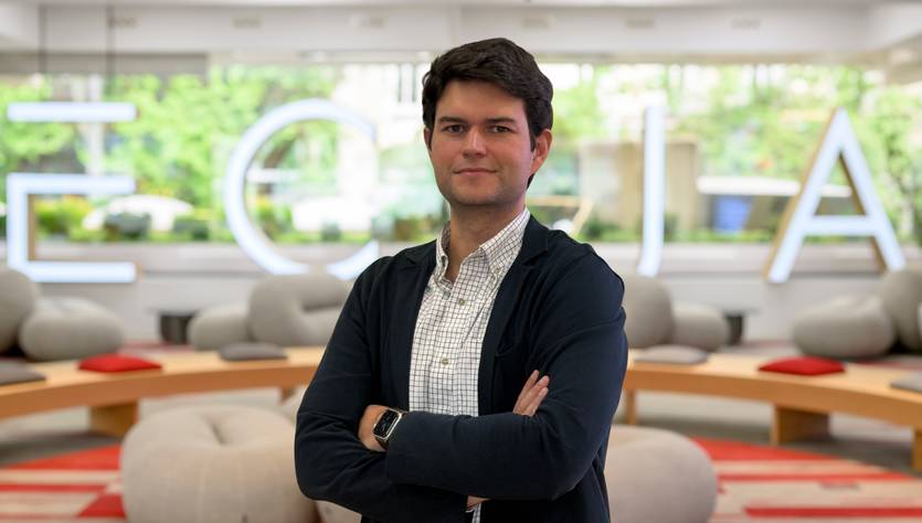 Un hombre con los brazos cruzados posando en un ambiente moderno y luminoso.