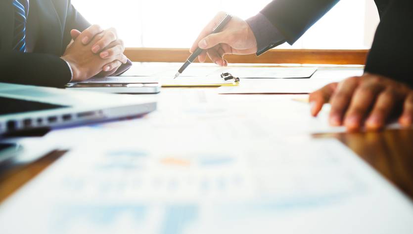 Dos profesionales en una reunión discutiendo sobre gráficos y datos.