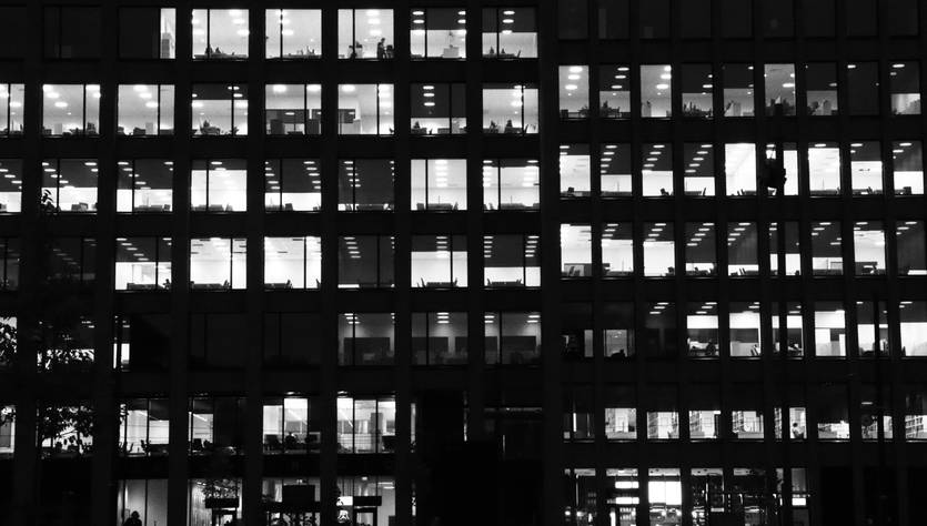 Edificio de oficinas iluminado en un entorno oscuro.