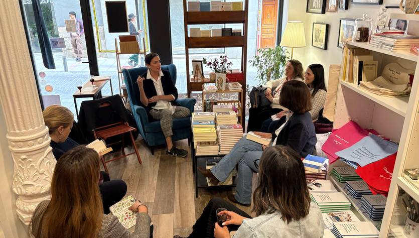 Un grupo de mujeres se encuentra en un ambiente acogedor escuchando a una oradora en una librería.