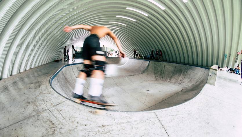 Un skater realiza una maniobra en un bowl dentro de una instalación cubierta.