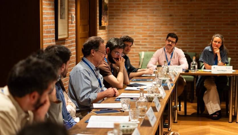 Un grupo de personas discute en una mesa durante una reunión en un ambiente acogedor.