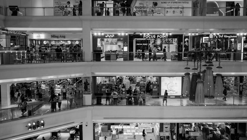 Una vista interior de un centro comercial con diferentes tiendas y personas en movimiento.