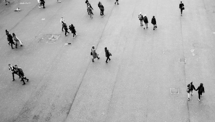 Una multitud de personas camina sobre una superficie pavimentada en una imagen en blanco y negro.