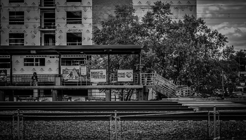 Una estación de tren en blanco y negro con edificios en construcción al fondo.