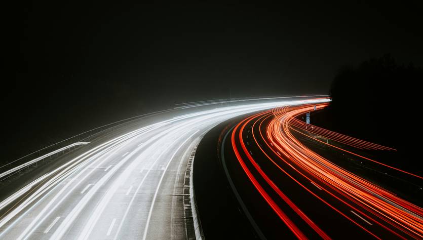 Una carretera nocturna en la que se pueden ver luces de vehículos en movimiento.