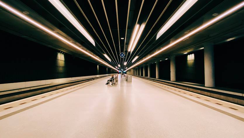 Una estación de tren moderna con líneas de luz que convergen hacia el fondo.