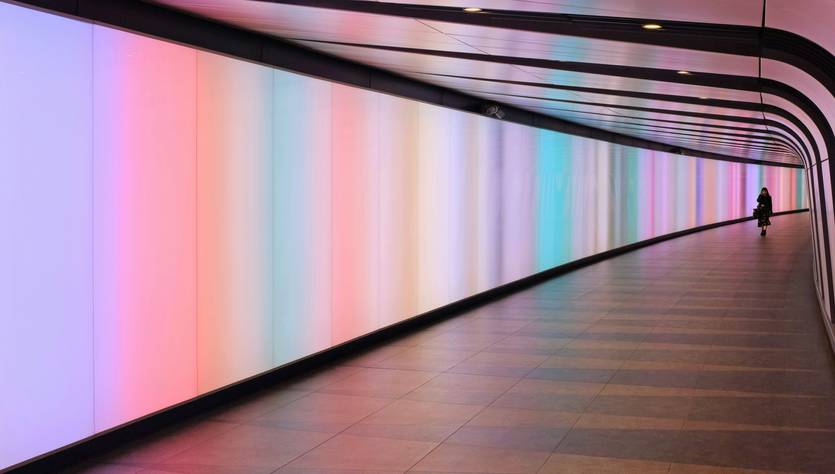 Un pasillo iluminado con luces de colores suaves que generan un ambiente moderno y acogedor.
