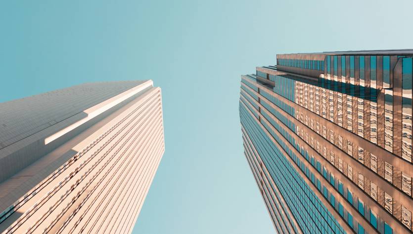 La imagen muestra una vista angular de edificios altos bajo un cielo despejado.