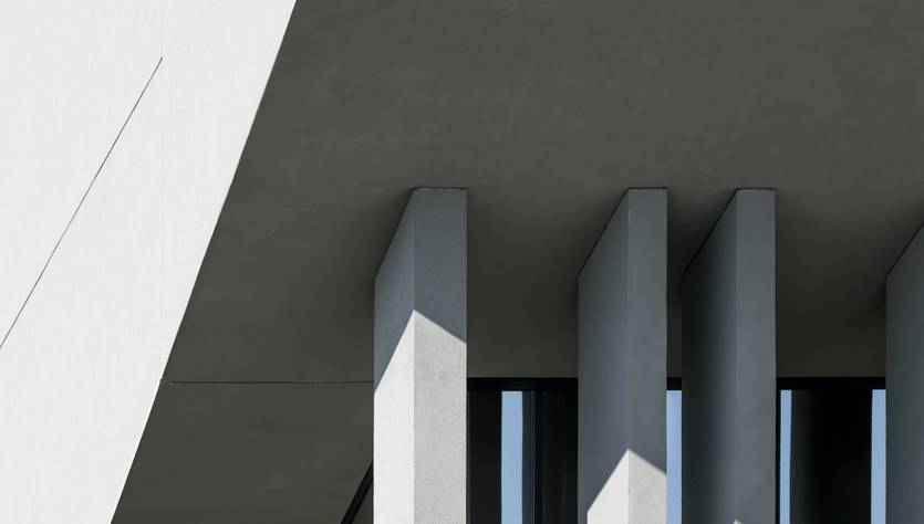 La imagen muestra una estructura arquitectónica contemporánea con líneas limpias y sombras marcadas.
