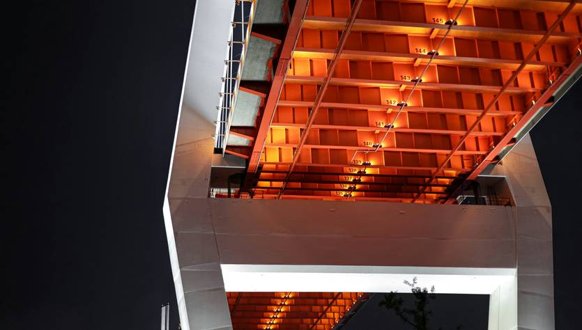 Puente iluminado con luz naranja visto desde abajo en una noche oscura.