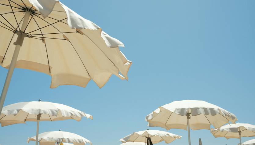 Una vista de sombrillas blancas en la playa bajo un cielo despejado.