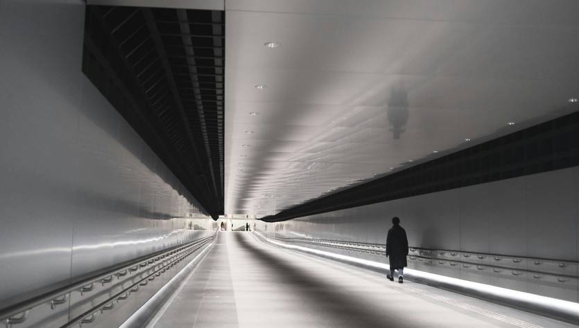 Un pasillo amplio y moderno con un único caminante al final.