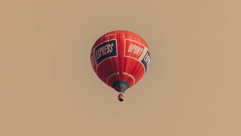 Un globo aerostático rojo con inscripción que vuela en el cielo.