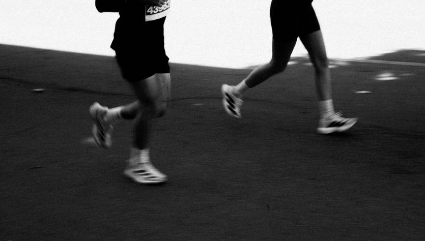 Dos corredores avanzan por una pista, capturados en una imagen en blanco y negro.
